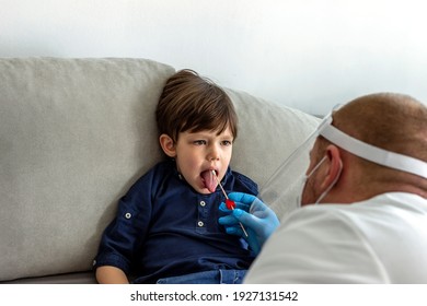 Caucasian Boy Having PCR Test During Coronavirus Pandemic. Doctor Takes A Cotton Swab Test From Child Mouth To Analyse For Covid-19. Pediatrician Using A Swab To Take A Sample From A Patient's Throat.