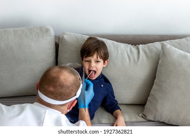 Caucasian Boy Having PCR Test During Coronavirus Pandemic. Doctor Takes A Cotton Swab Test From Child Mouth To Analyse For Covid-19. Pediatrician Using A Swab To Take A Sample From A Patient's Throat.