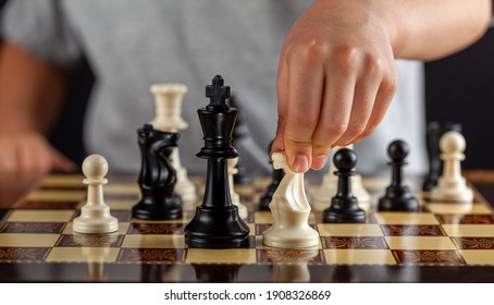 A Caucasian Boy Is Holding A White Knight Chess Piece During A Game. He Will Make A Move. Dark Background Image For Determination, Concentration, Focusing, Calculation Risk Taking Behavior Concepts