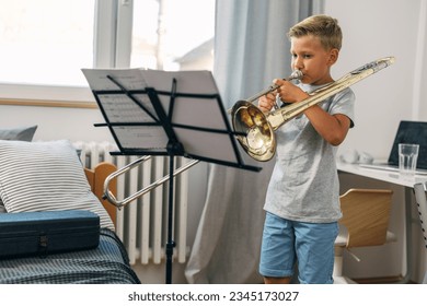 Niño caucásico practicando trombona en casa.