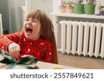 Caucasian boy in red pijamas crafing decorations or opening presents  at home candid shot