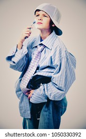 Caucasian Boy Wearing His Dad's Shirt, Jeans And Tie On Light Background. He Is Wearing Big Adult Size Clothes Which Are Too Big For Him.