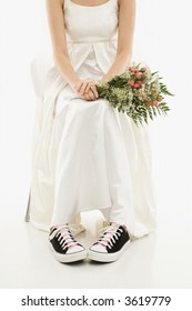 Caucasian Bride Holding Bouquet Exposing Her Tennis Shoes.