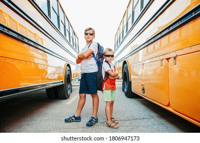 Caucasian Brothers Students Near Yellow School Bus. Cool Kids In Sunglasses Going Back To School In September. Education System And Learning. Support And Friendship. 