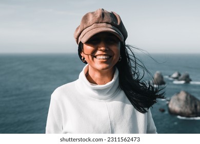 caucasian brunette girl with long black hair smiling happy looking at camera in a quiet place near sea rocks, nugget point, new zealand - Shutterstock ID 2311562473