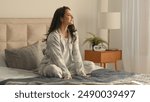 Caucasian brunette woman sitting on bed bedroom home touching neck massage good morning calm comfortable cozy inside awake healthcare in pajamas relaxing smiling wellbeing peaceful apartment recovery