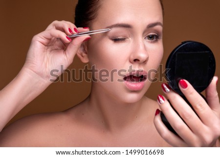 Caucasian brunette woman tweeze her eyebrowns. Close up portarait. Skin care  concept
