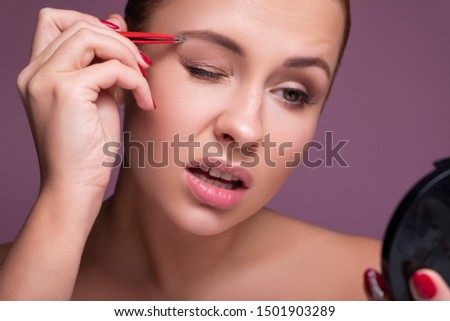 Caucasian brunette woman tweeze her eyebrowns. Close up portarait. Skin care  concept