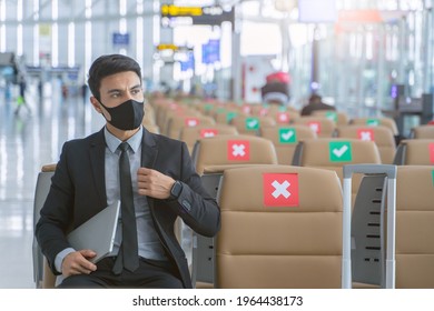 Caucasian Business Man Is Carrying Laptop Computer While Waring Mask And Keep Distance From Another Passenger. New Normal And Social Distancing Concept In Airport. 