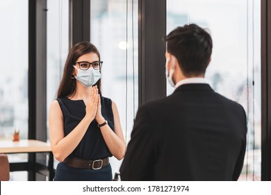 Caucasian Business People In Office Wear Protective Face Mask Greeting In Thai Style  (Wai) Instead Of Hand Shake. Concept Of New Normal Greeting To Prevent Covid 19 Outbreak