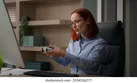 Caucasian business woman office worker at workplace break pause work addicted video game playing console controller businesswoman play online while nobody see girl get caught pretend working smiling - Powered by Shutterstock