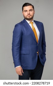 Caucasian Businessman With Blue Suit And Yellow Tie, Grey Background