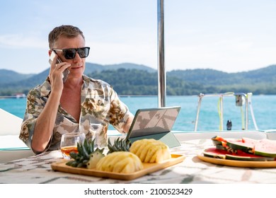 Caucasian businessman using mobile phone and working on digital tablet for online corporate business while catamaran boat sailing. Handsome man relax and enjoy outdoor lifestyle on summer vacation - Powered by Shutterstock