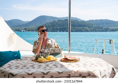 Caucasian businessman using mobile phone and working on digital tablet for online corporate business while catamaran boat sailing. Handsome man relax and enjoy outdoor lifestyle on summer vacation - Powered by Shutterstock