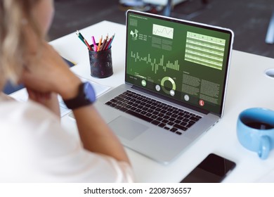 Caucasian Businesswoman Analyzing Multiple Graphs Over Laptop On Desk In Office. Unaltered, Report, Finance, Office, Business, Investment And Technology Concept.