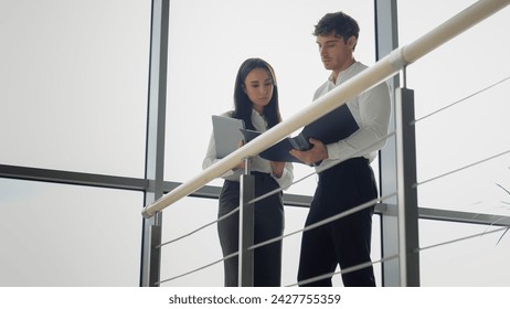 Caucasian businesswoman and businessman discuss documents in company hall business people male and female woman and man coworkers partners colleagues manager discussing data from papers office lobby - Powered by Shutterstock