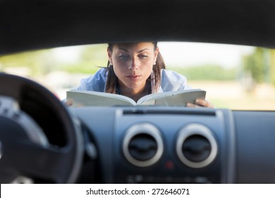 Kaukasische Geschäftsfrau hat ein Autoproblem und liest eine Autounterweisung