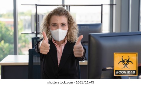 Caucasian Businesswoman With Medical Mask For Coronavirus Covid 19 Protection Working In Office And Thumb Up Showing Support To Wearing Mask With Covid 19 Sign