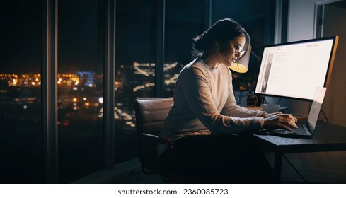 Caucasian businesswoman working late at her desk, typing on her laptop in a technology-driven office. Young female professional focusing on her project, ensuring it's completed before the deadline.