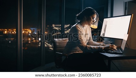 Caucasian businesswoman working late at her desk, typing on her laptop in a technology-driven office. Young female professional focusing on her project, ensuring it's completed before the deadline.