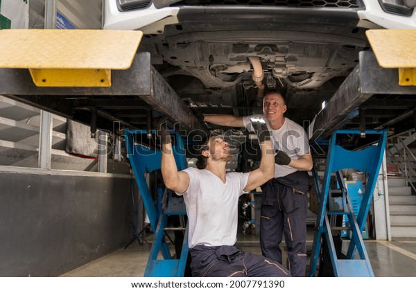 Caucasian car mechanic and automotive team\
using torch to check a suspension system parts in tire shop. Senior\
professional vehicle mechanic repair automobile in garage workshop.\
Auto repair service\

