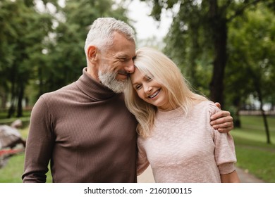 Caucasian cheerful mature couple husband and wife hugging embracing togehter on a romantic date while walking in city park. - Powered by Shutterstock
