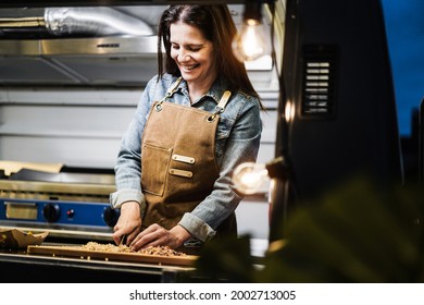 Caucasian Chef Woman Working Inside Food Truck At Night Time Preparing Dinner Food - Summer Job Concept - Focus On Face