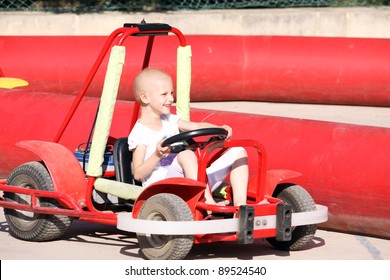 A Caucasian Child Undergoing Cancer Teatment Having Fun On A Go Cart At A Fun Fair