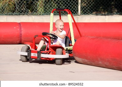 A Caucasian Child Undergoing Chemotherapy Treatment Due To Cancer Having Fun On A Go Cart At A Fun Fair