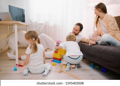 caucasian children, son and daughter playing on floor together while their parents relax or busy with their own affairs at home, happy family concept - Shutterstock ID 1595403508