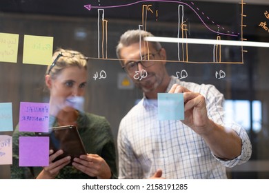 Caucasian colleagues seen through glass wall planning strategy together in meeting room. unaltered, creative business, teamwork and modern office concept.