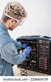 Caucasian Computer Technician Cleaning Inside Of A Cabinet With Air Compressor. Vertical Ophoto