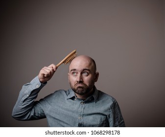 Caucasian Confused Bald Man Trying Hair Brush