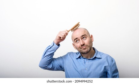 caucasian confused bald man trying hair brush