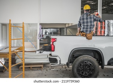 Caucasian Construction Contractor Worker With Large Hummer Taking Short Work Brake Seating On His Pickup Truck Cargo Bed Side. 