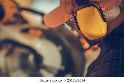 Caucasian Construction Worker In His 40s Wearing Noise Cancellation Safety Headphones While Working Within Construction Site.