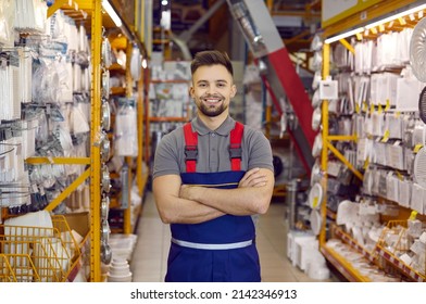 Caucasian consultant in uniform at hardware store. Male standing next to shelves with tools at DIY store. Handsome bearded guy is ready to help customers to choose tools for different home repairs