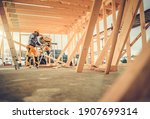 Caucasian Contractor Carpenter Worker in His 40s Using Commercial Grade Circular Saw in Construction Zone. Industrial Theme. Wooden Skeleton Framing Building.