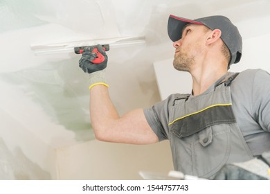 Caucasian Contractor In His 30s Patching Drywall Walls. Construction Site.