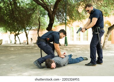 Caucasian Cops Using Their Guns While Making An Arrest Of A Violent Criminal Suspect After A Chase Outdoors 