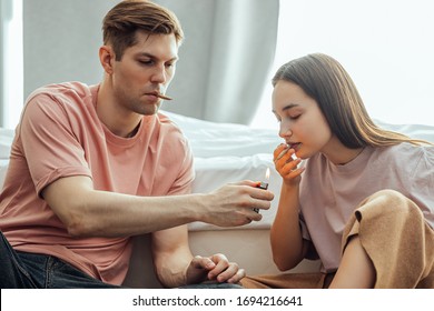 caucasian couple catch a buzz from using cannabis, marijuana. man and woman enjoy using drugs together, they warm bong with cannabis and smoke it. drugs treatment, ganja and hemp medicine concept