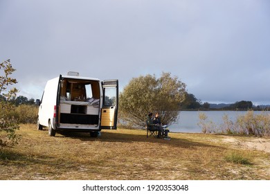 Caucasian couple eating breakfast on a lake with a camper van living van life social distancing on a Dam in Portugal