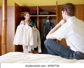 Caucasian Couple Getting Dressed In The Morning, With Woman Choosing Shirt. Horizontal Shape, Front View, Three Quarter Length