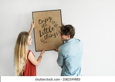 Caucasian Couple Hanging A Frame On White Wall