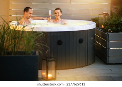 Caucasian Couple Having Fun and Lazy Time Inside a Garden Hot Tub During Summer Evening. Garden SPA Theme.