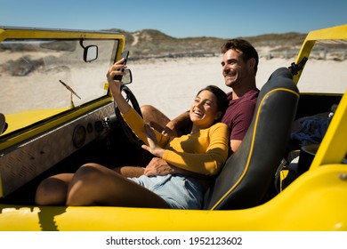 Caucasian couple on a beach buggy by the sea taking selfie. beach break on summer holiday road trip. - Powered by Shutterstock