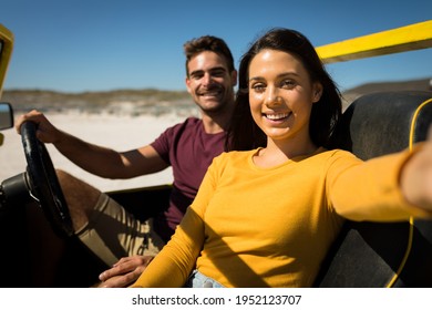 Caucasian couple on a beach buggy by the sea taking selfie. beach break on summer holiday road trip. - Powered by Shutterstock