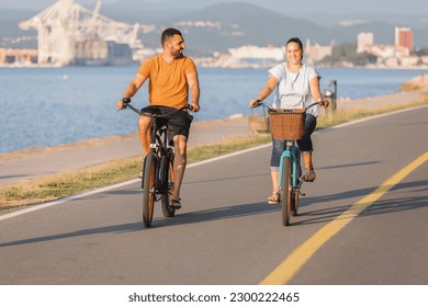 Caucasian couple on a relaxing cycle ride along the seacoast, enjoying the sea air, breeze, and view - Powered by Shutterstock