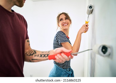 Caucasian couple painting wall in new house