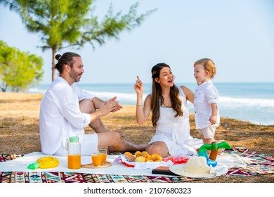 Caucasian couple picnic party with little child boy together on tropical beach. Happy family father and mother with cute baby son enjoy and fun outdoor activity lifestyle on summer travel vacation